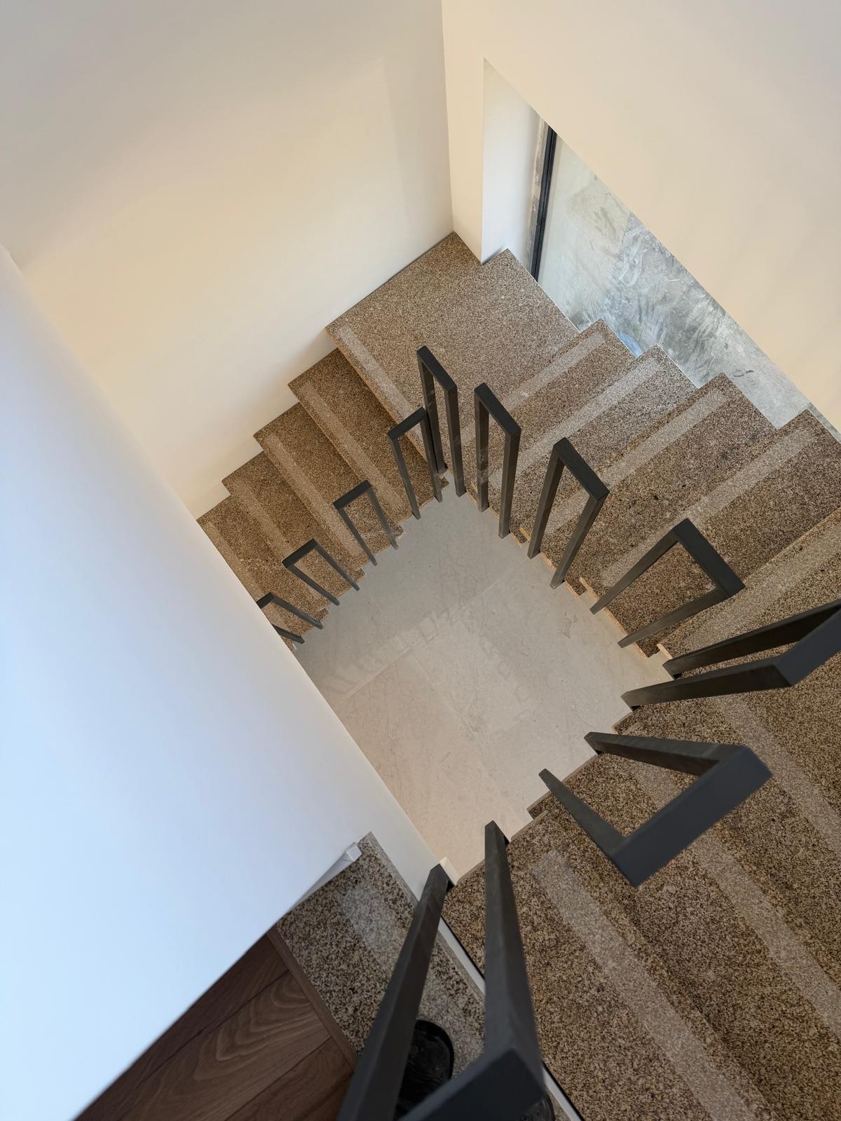 Escada interior em granito com corrimão e guardas metálicas pretas